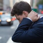 Close-up of a person holding their neck in discomfort, representing the struggle of proving invisible injuries