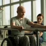 Person undergoing rehabilitation therapy in a wheelchair, with a physiotherapist assisting in their recovery process.